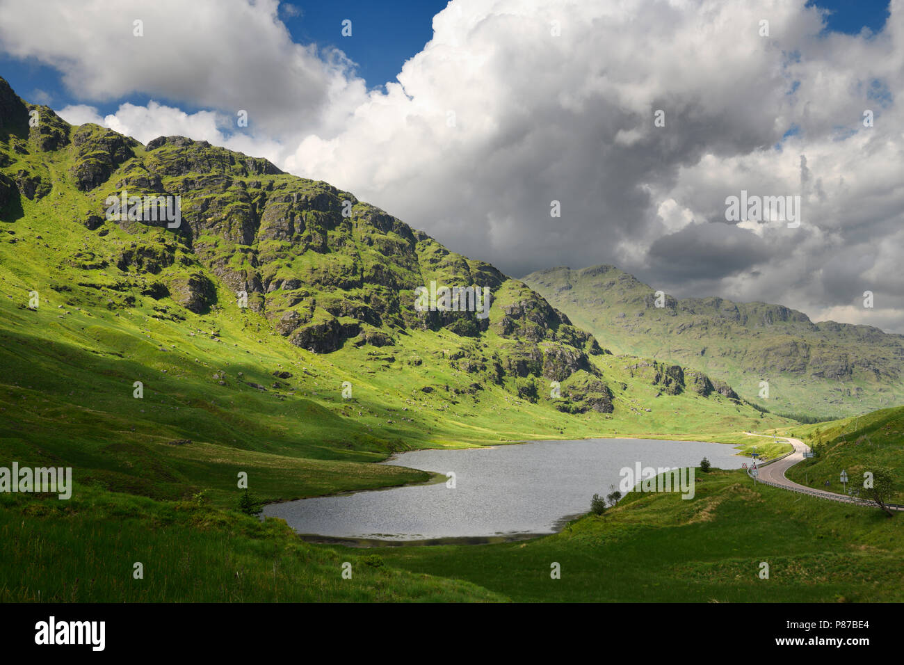 Beinn un Lochain e Binnein un Fhidhleir montagne delle Alpi a Arrochar in sun con il Loch Restil a riposo ed essere grati di pietra commemorativa in Scozia Foto Stock