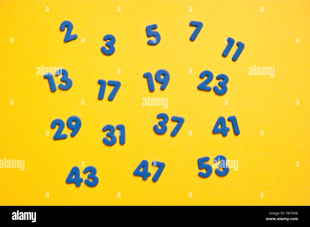 Prime sedici numeri primi, blu su giallo Foto Stock