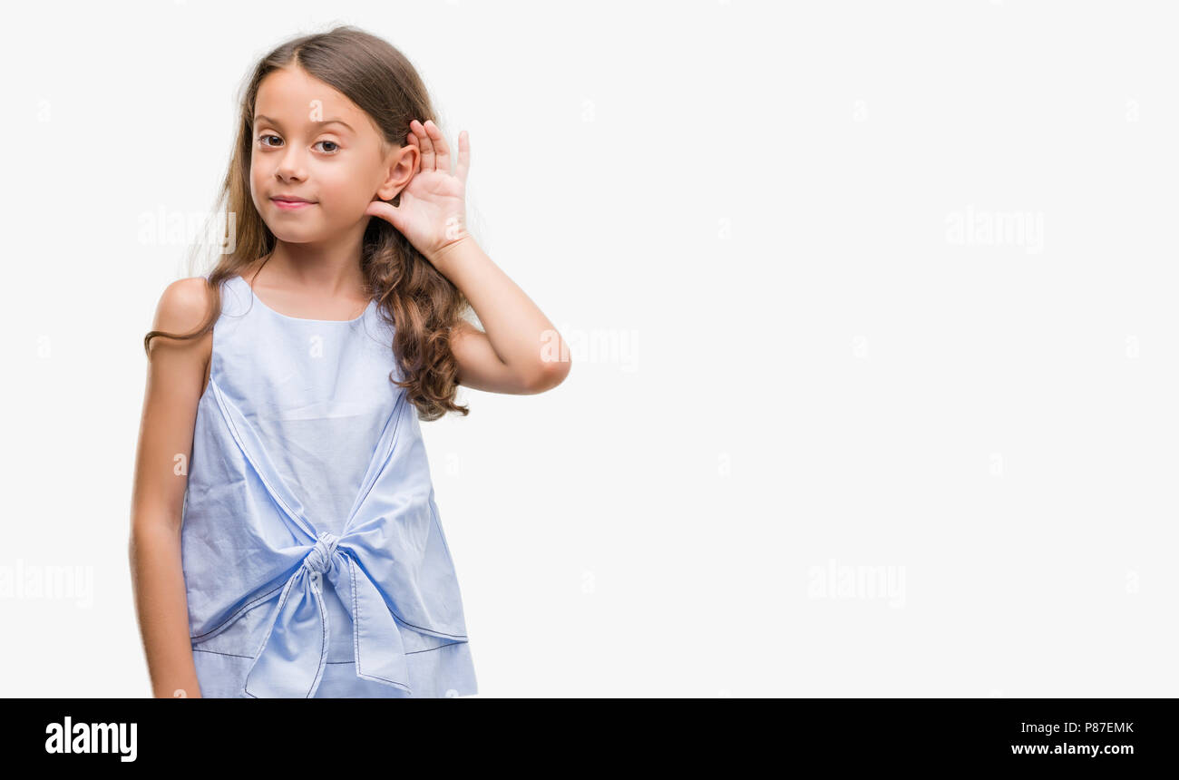 Brunette ispanico ragazza sorridente con la mano sul orecchio in ascolto di un audizione di rumor o gossip. Concetto di sordità. Foto Stock