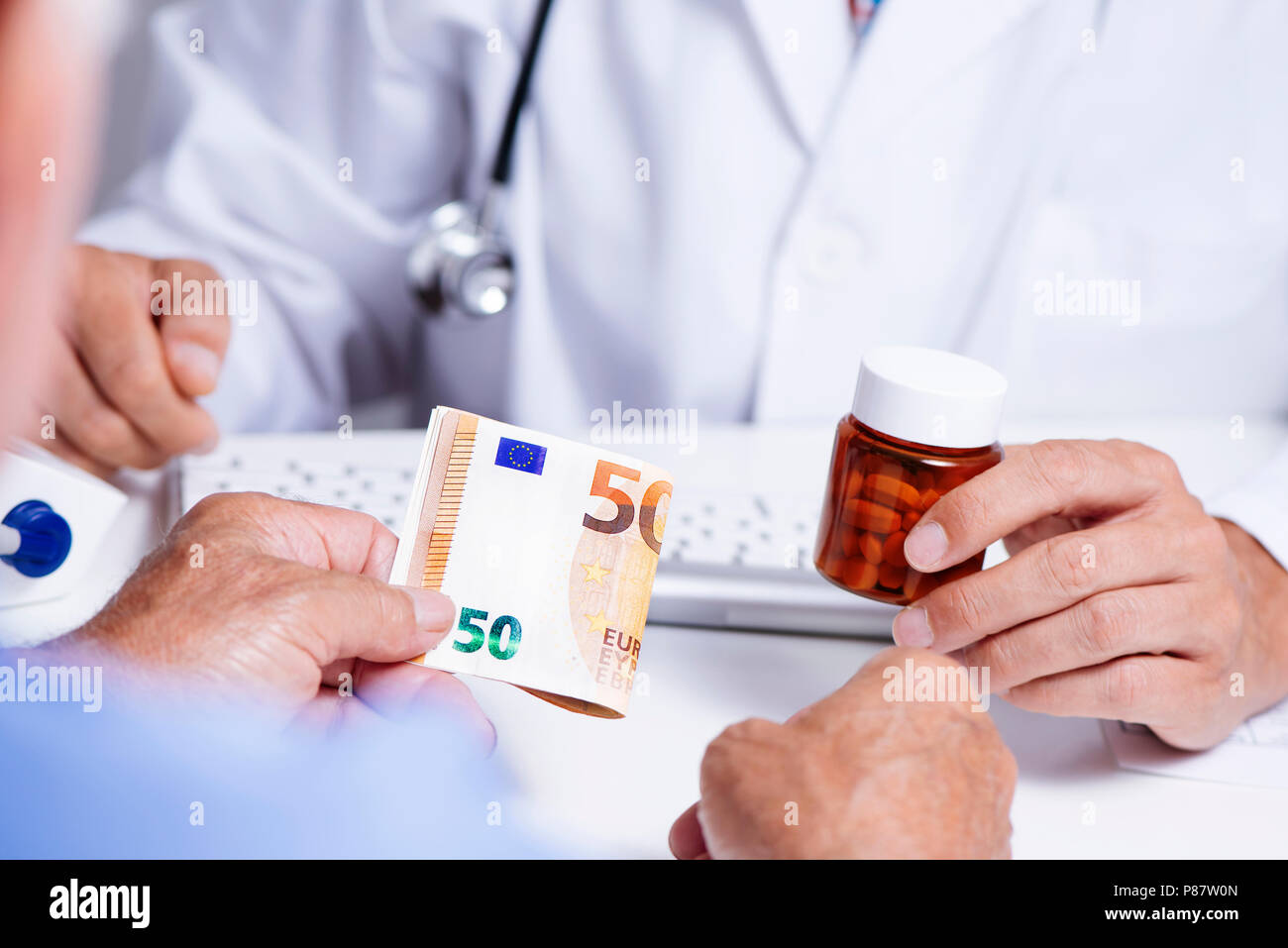 Primo piano di un medico caucasica uomo in camice bianco, dando una bottiglia di pillole a un senior caucasica uomo paziente, chi è che dà al medico un 50 euro Foto Stock