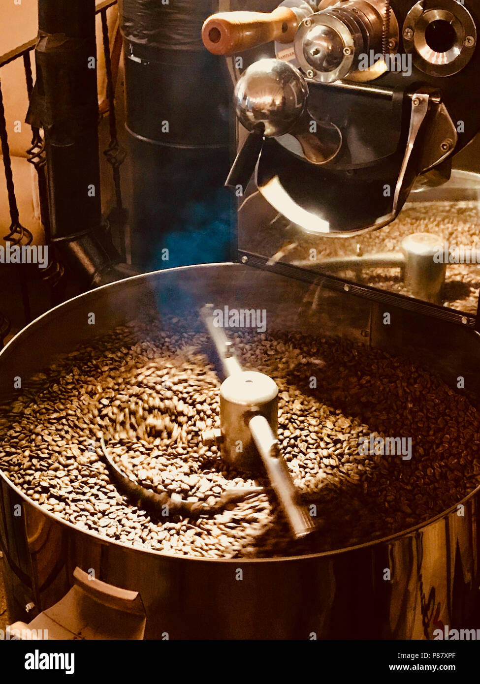 Appena tostato aromatici chicchi di caffè in una torrefazione macchina. Alimenti biologici. Foto Stock