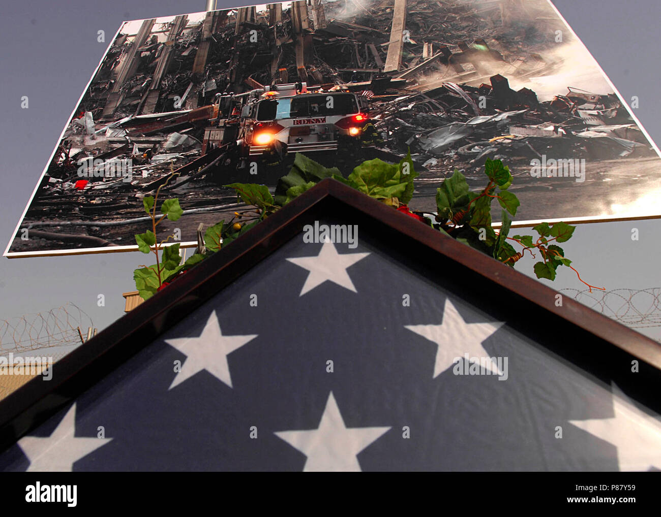 4 soldati ID ricordare 9-11 vittime DVIDS115083. Ripiegata di bandiera americana si siede sotto una foto della devastazione delle Torri Gemelle a New York City. Membri della MND-B si sono riuniti per ricordare le vittime degli attacchi di 9/11 su Camp Liberty, Bagdad il 7 settembre 11, 2008. Foto Stock
