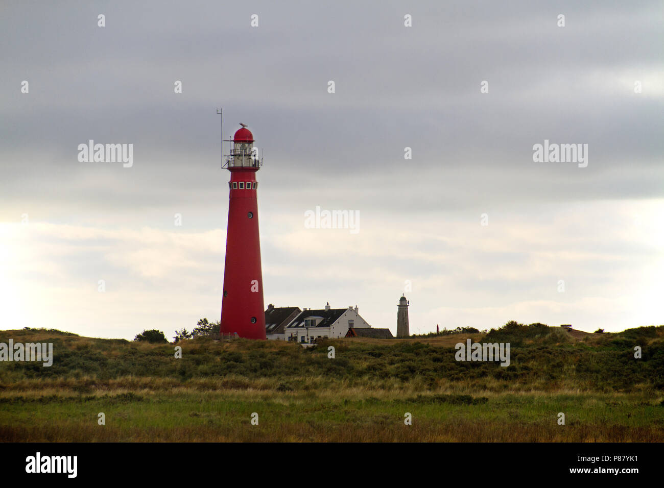 Faro rosso nelle dune dell'isola olandese Schiermonnikoog, accanto ad essa la casa bianca del detentore, a distanza di un secondo faro Foto Stock