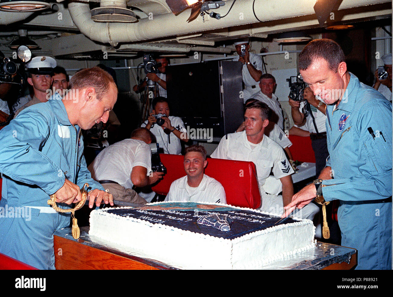 Gli astronauti Charles Conrad Jr. (sinistra) e L. Gordon Cooper Jr preparare per affettare in la grande torta preparata per loro dai cuochi a bordo della portaerei USS Lake Champlain. Foto Stock