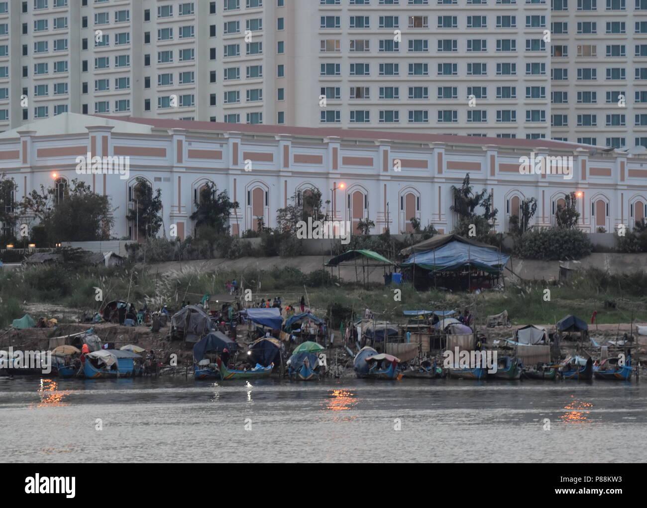 Il contrasto di hotel di lusso e barche da pesca e la povertà delle minoranze musulmane lungo il fiume Mekong in Phnom Penh Cambogia Foto Stock
