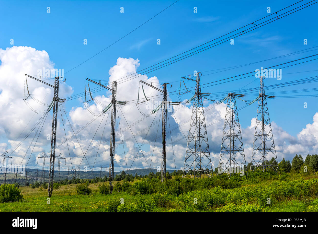 Alta tensione le torri di trasmissione di fila. Energia elettrica sul filo il paesaggio rurale dello sfondo. Foto Stock