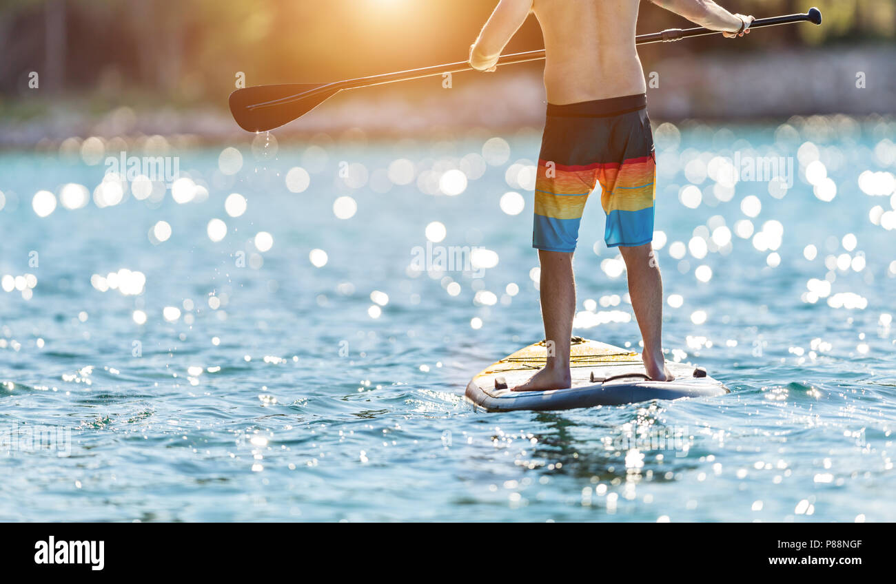 Dettaglio del giovane uomo in piedi sul paddleboard. Paddleboarding è il moderno modo di trasporto e di attività dell'acqua sport. Foto Stock