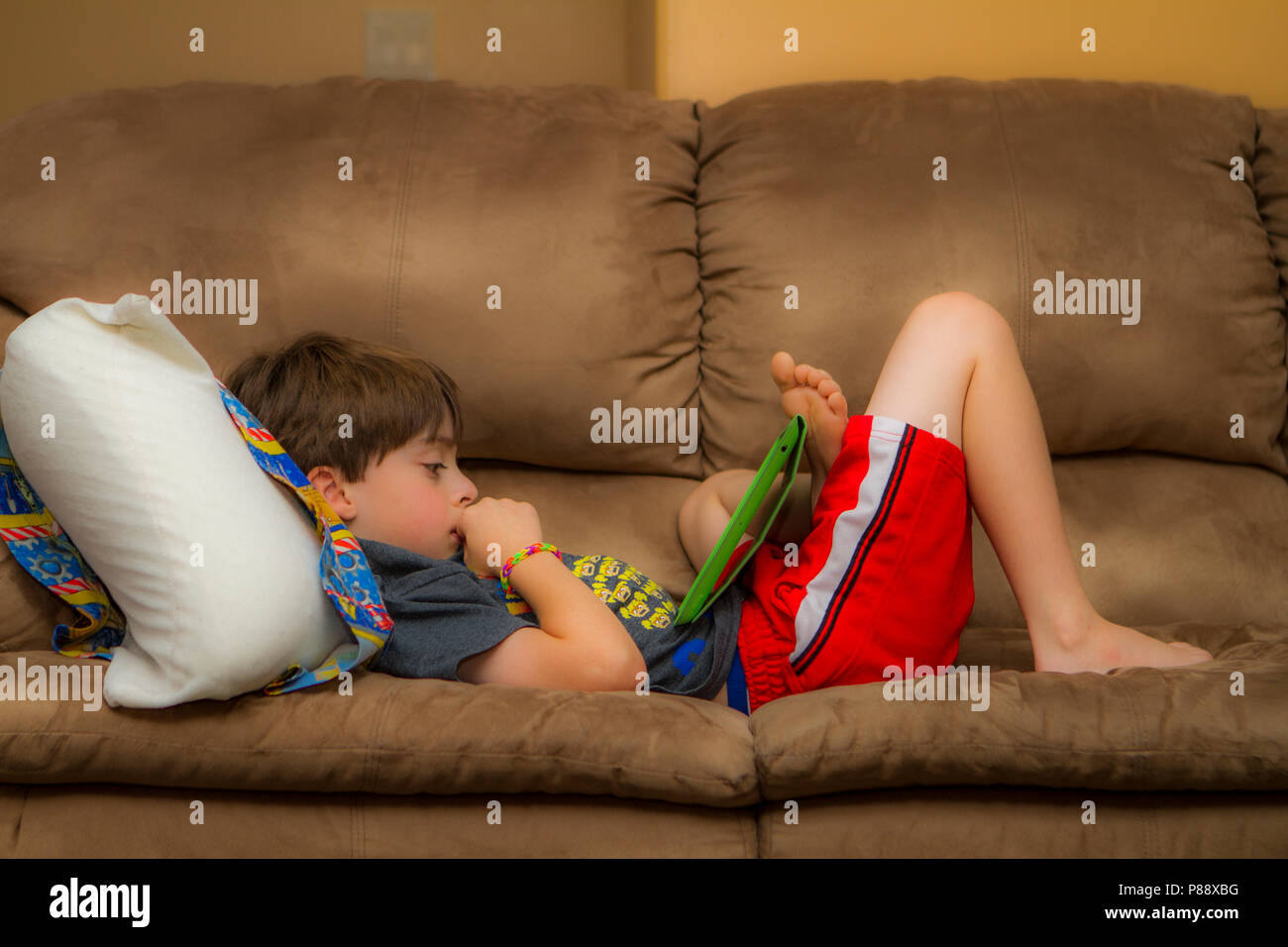 Modello rilasciato 9 anno vecchio ragazzo, rilassante sul lettino, con la compressa. Cranbrook, British Columbia, Canada. Modello di Rilascio # 105 Foto Stock