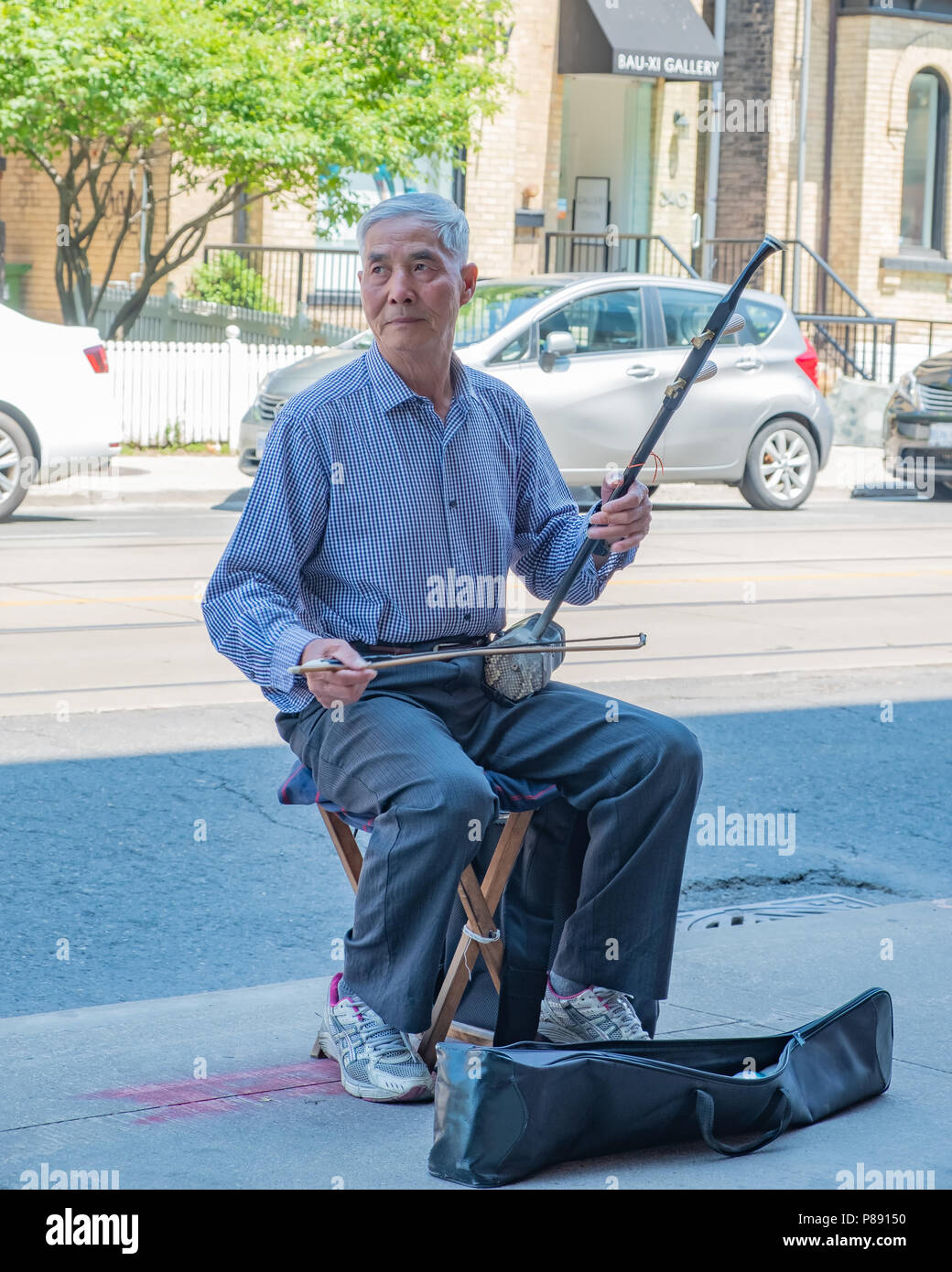 Anziani uomo cinese suona uno strumento tradizionale della Cina su un Street nel quartiere di Chinatown di Toronto. Foto Stock