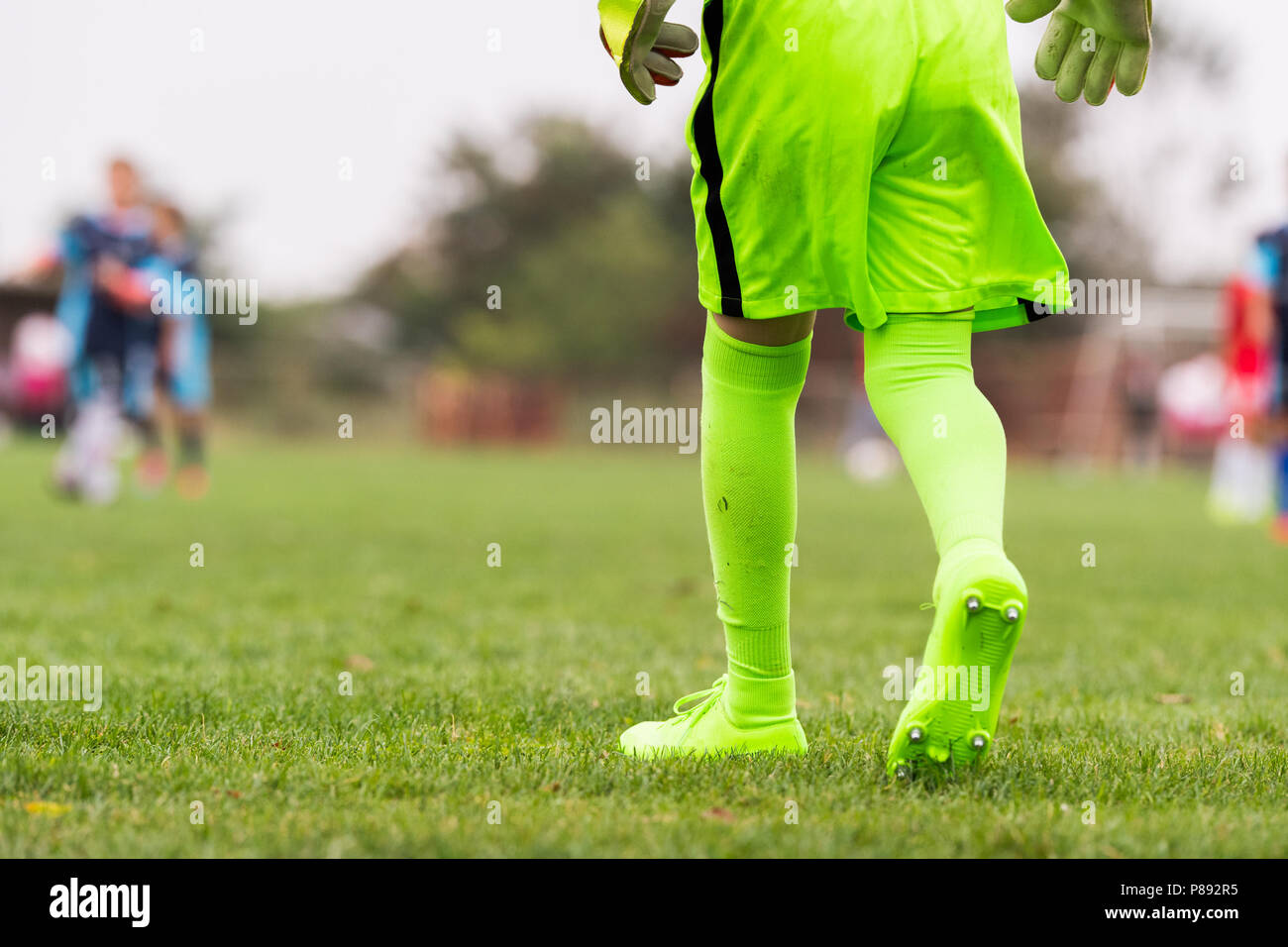 Kids soccer football - little portiere in verde Goalkeeper Jersey al campo di calcio con i guanti di corrispondenza Foto Stock
