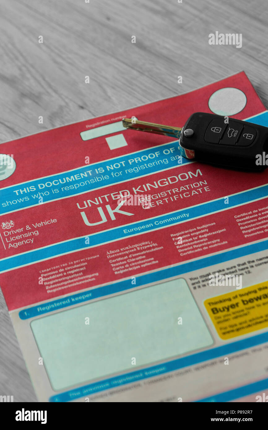 V5C car log book con chiave elettronica portachiavi su un grigio Sfondo di legno Foto Stock
