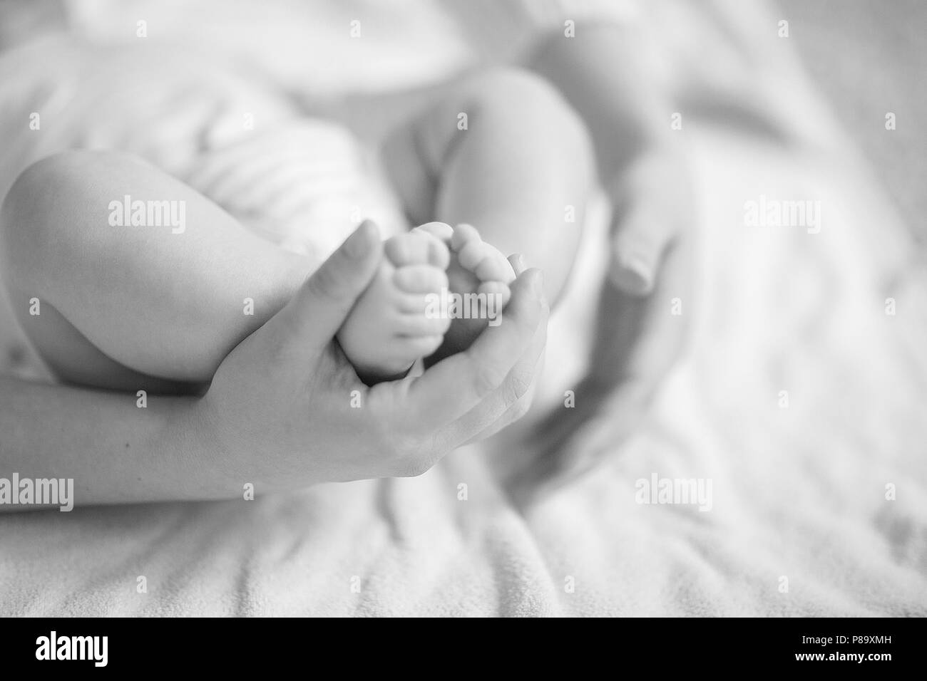 Concetto di tenerezza:una madre tenendo il piede del neonato Foto Stock