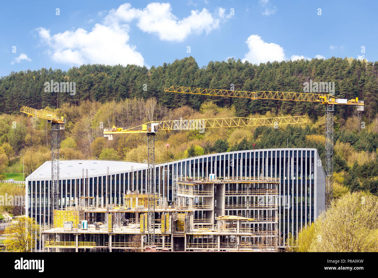 Vista panoramica di industriale sito in costruzione di gru sullo sfondo di verdi colline Foto Stock