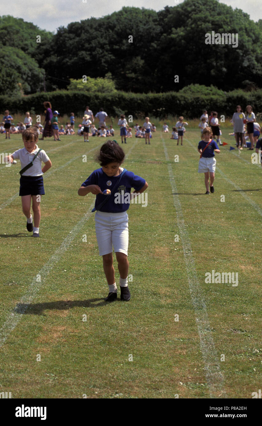 I bambini che partecipano a uovo e cucchiaio gara presso la scuola primaria la giornata dello sport Foto Stock