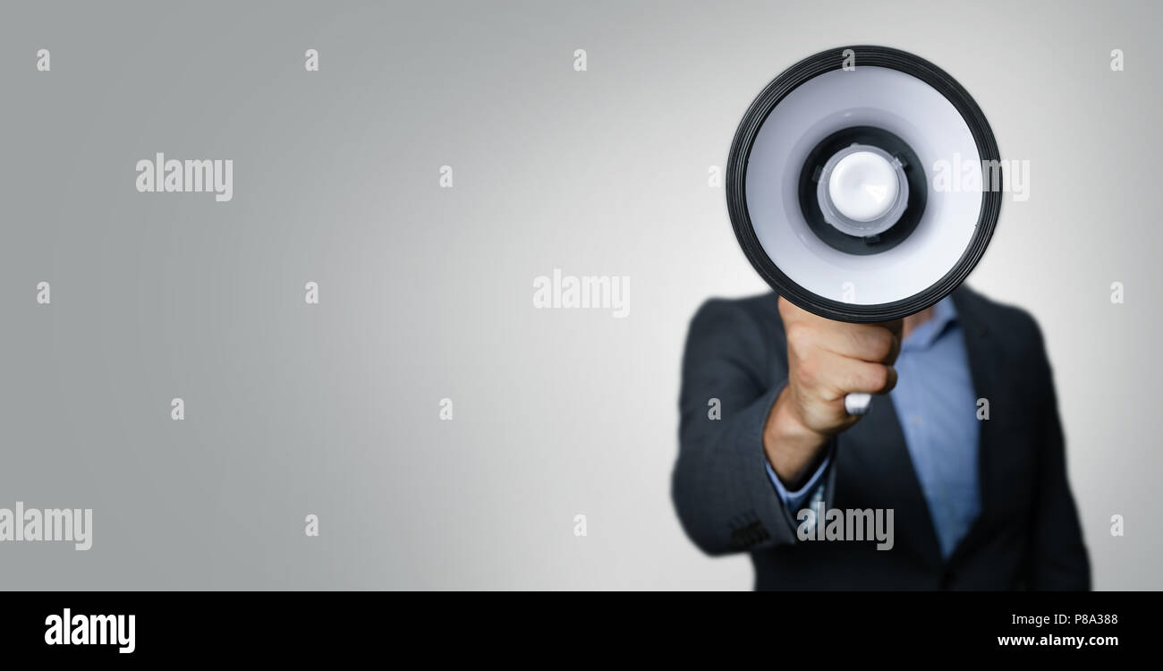 Annuncio - imprenditore con megafono di fronte faccia su sfondo grigio Foto Stock