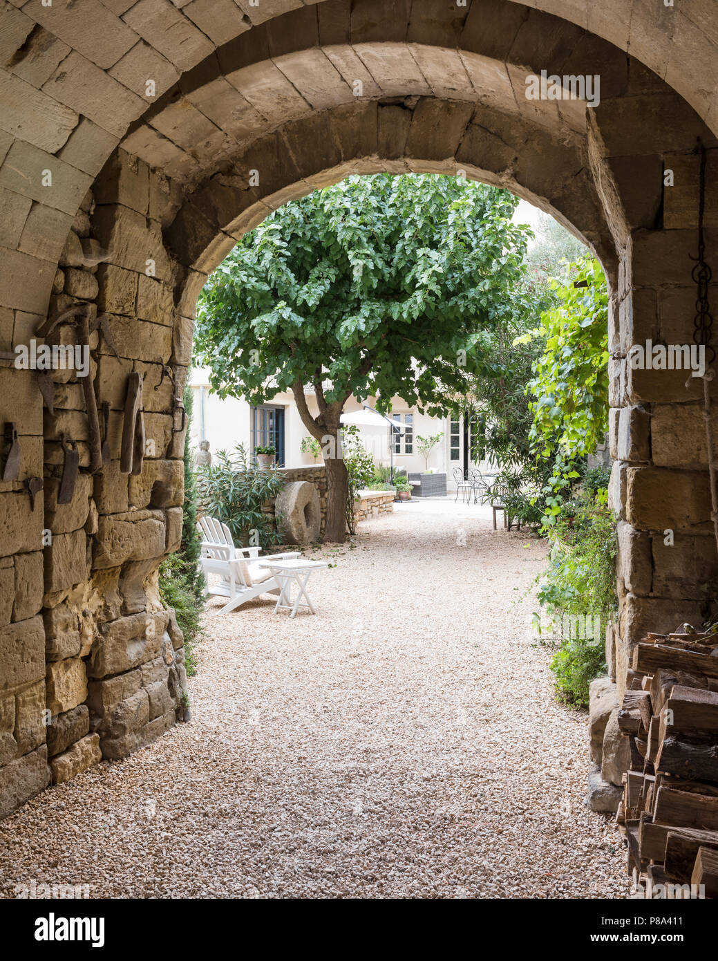 Arco in pietra entrata viene appeso con antichi attrezzi agricoli lasciati dai precedenti proprietari. Foto Stock
