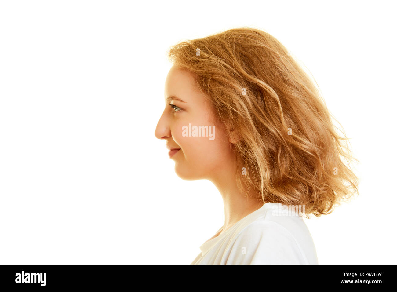 La faccia di un giovane biondo donna sorridente lateralmente nel profilo Foto Stock