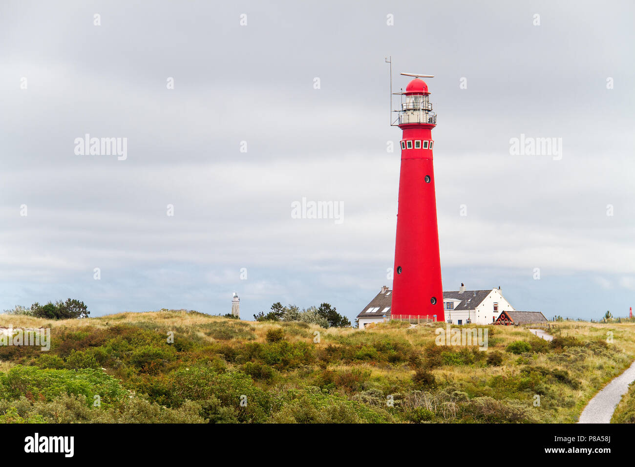 Faro rosso nelle dune dell'isola olandese Schiermonnikoog, accanto ad essa la casa bianca del detentore, a distanza di un secondo faro Foto Stock