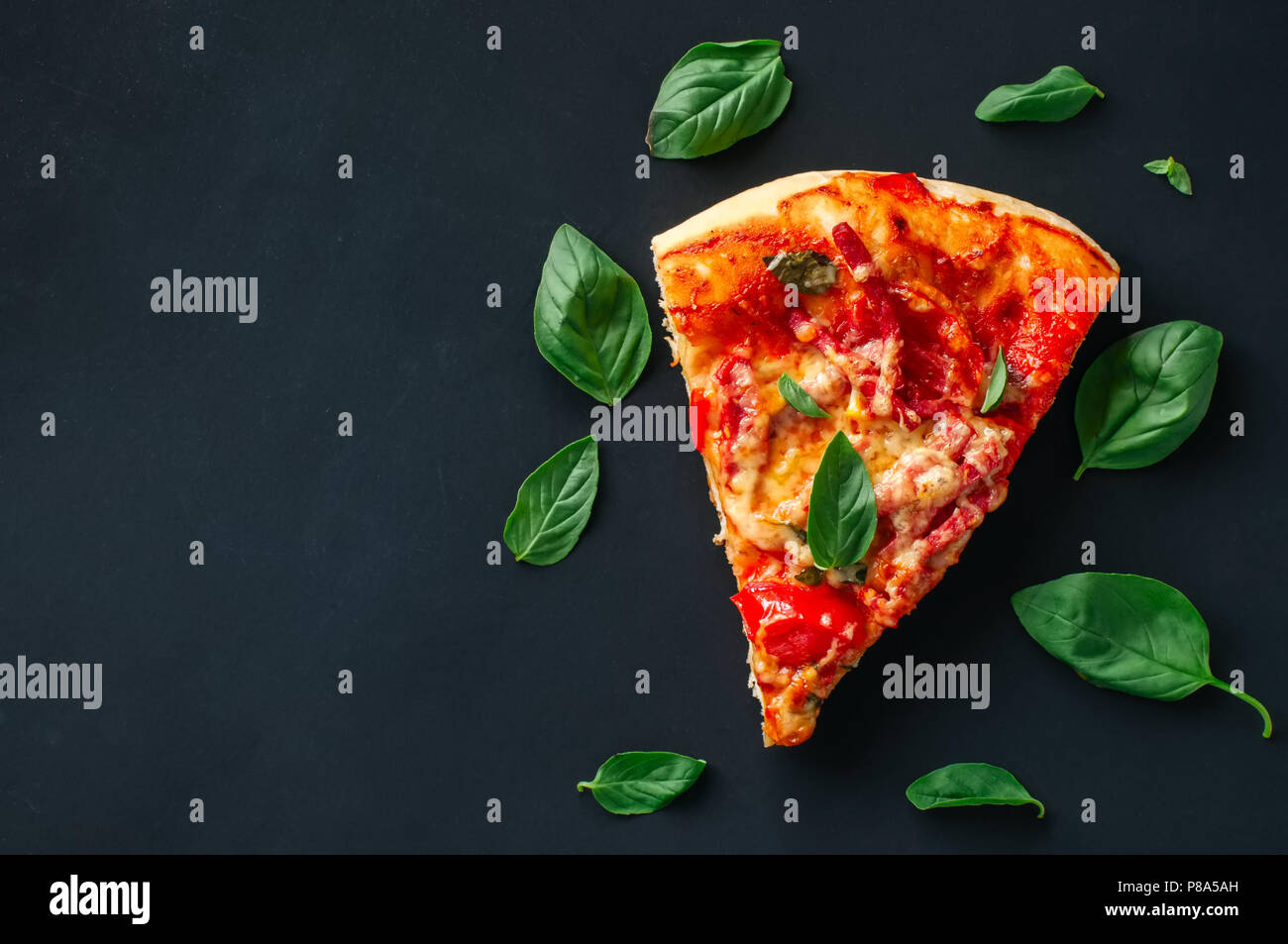 Un pezzo di salame pizza su sfondo nero. Vista superiore, piana, laici copia spazio. Foto Stock