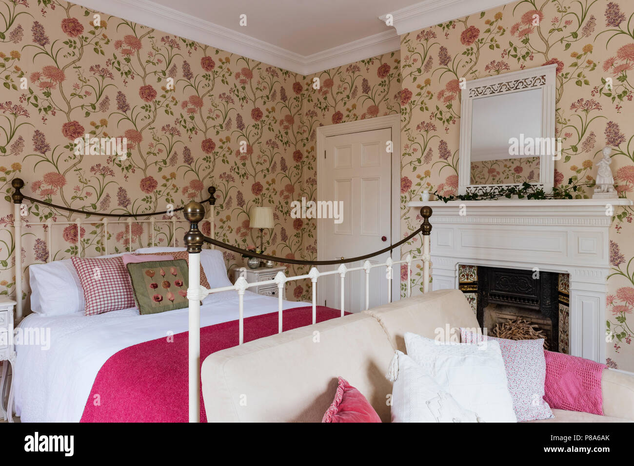 Rosa luminoso coperta sul metallo letto incorniciati in Regency home con Sanderson estiva della carta da parati ad albero Foto Stock