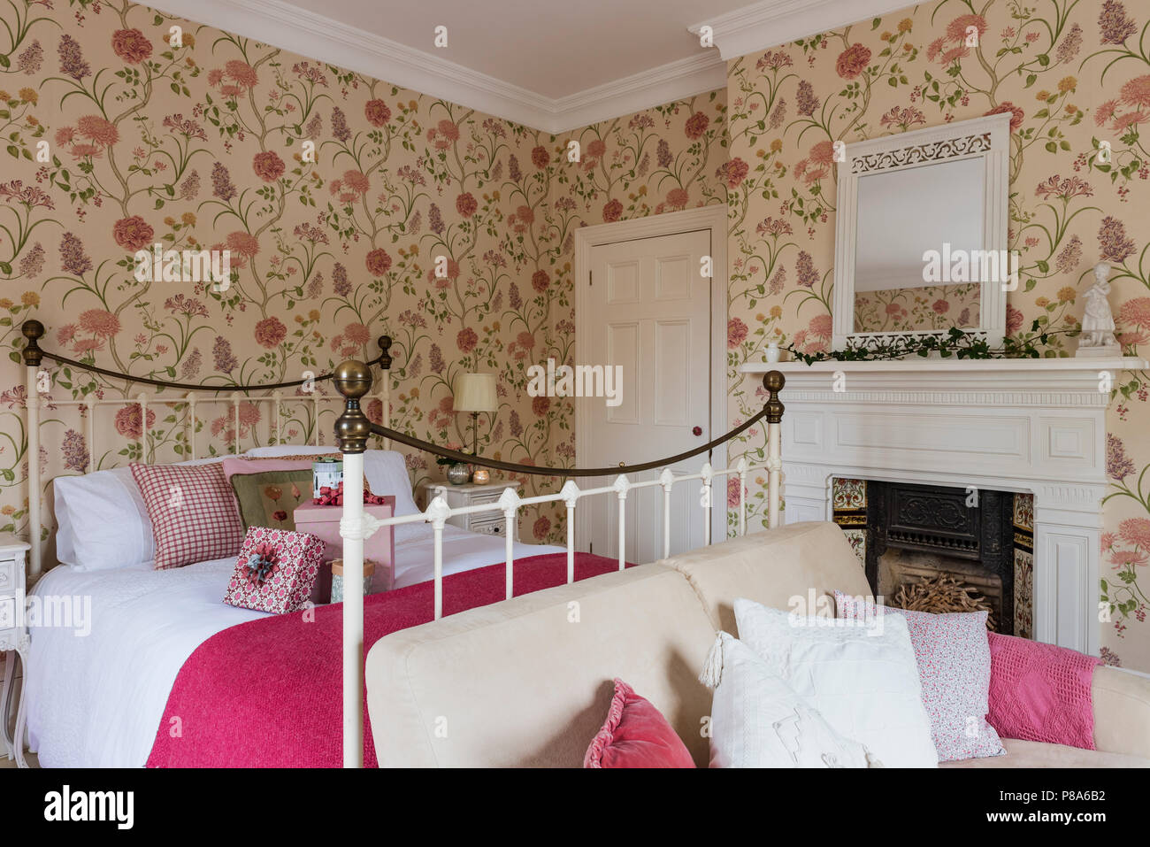 Rosa luminoso coperta sul metallo letto incorniciati in Regency home con Sanderson estiva della carta da parati ad albero Foto Stock