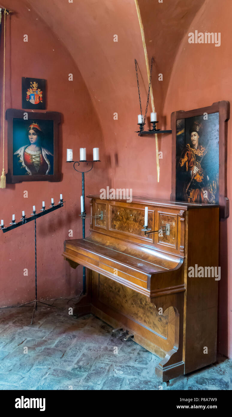 Il vecchio pianoforte in legno sorge in un angolo delle pareti rosse tra antichi  candelabri . Per il vostro design Foto stock - Alamy