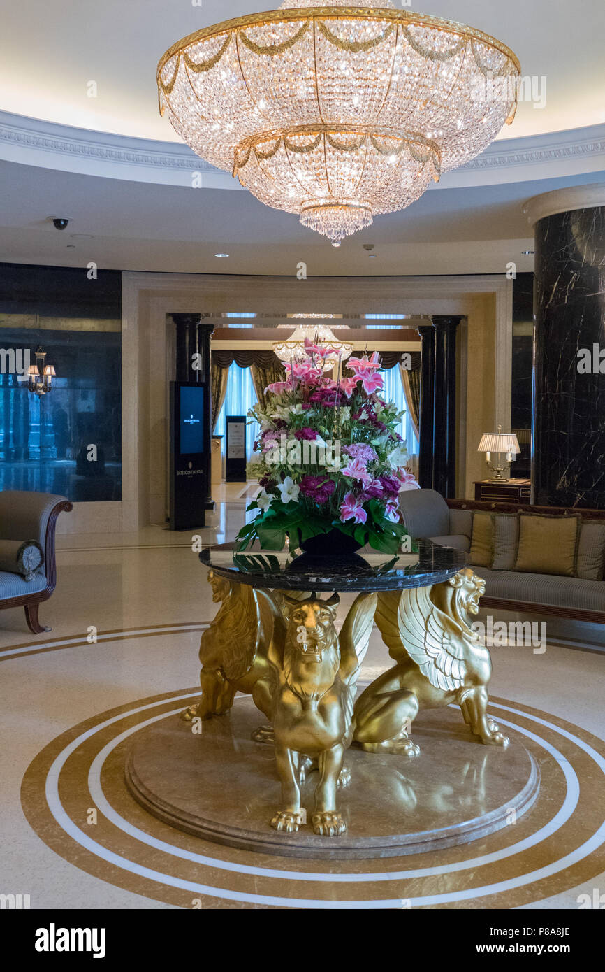 Interni di lusso nella lobby dell'hotel. La copertura del tavolo si trova su tre tigri con le ali con un vaso in piedi su di esso con un bel bouquet di f Foto Stock
