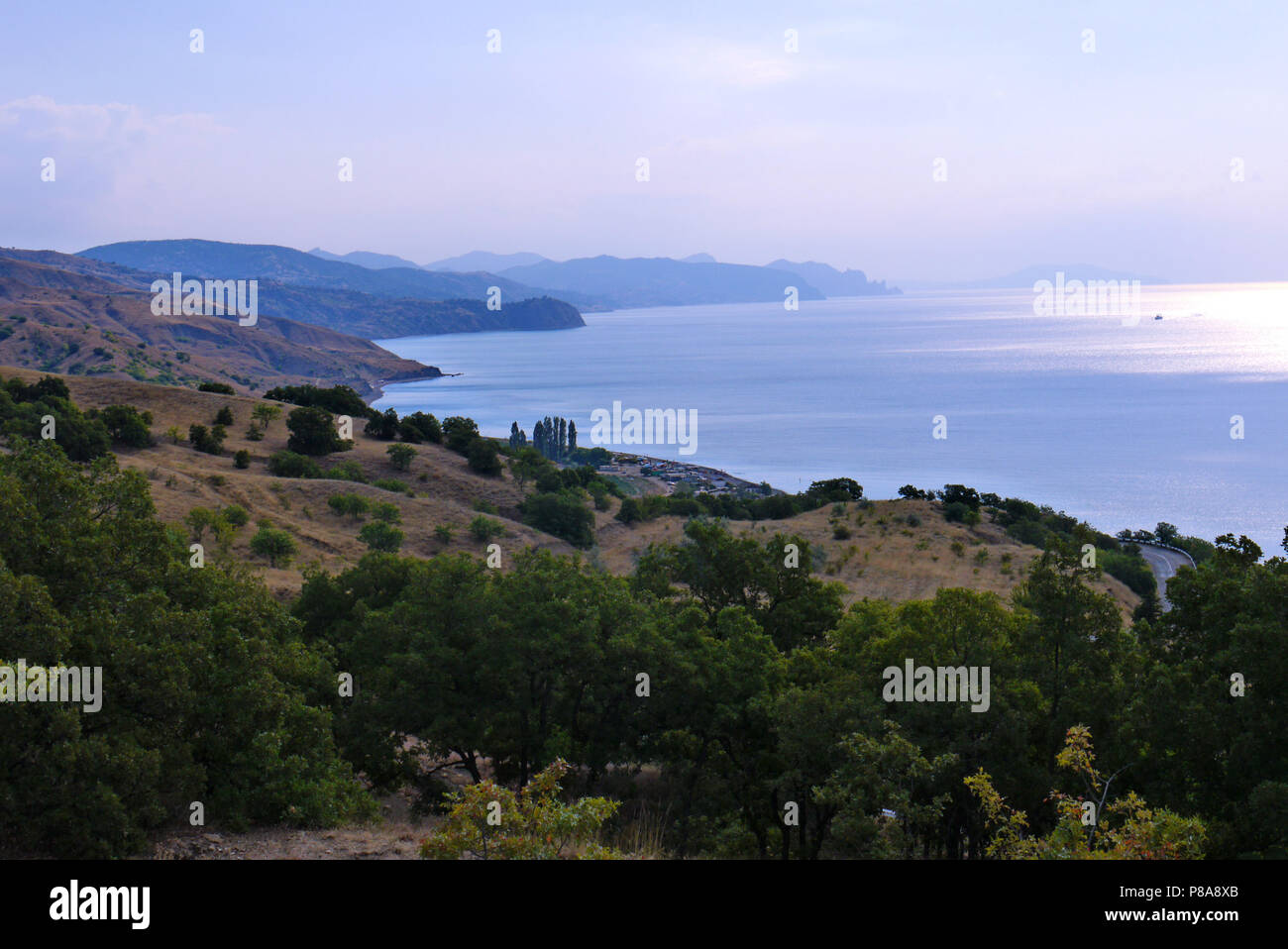 Un mare calmo baia con una striscia costiera di colline pietrose raggiungendo l'acqua stessa. . Per il vostro design Foto Stock