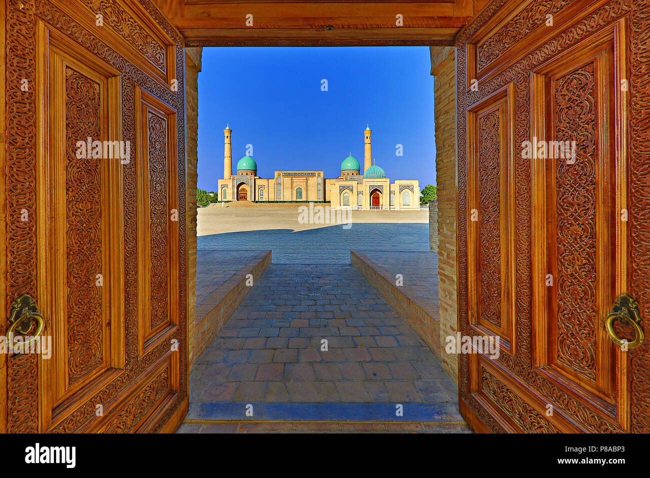 Vista su Khast Imam moschea al crepuscolo, attraverso porte di legno, Tashkent, Uzbekistan. Foto Stock