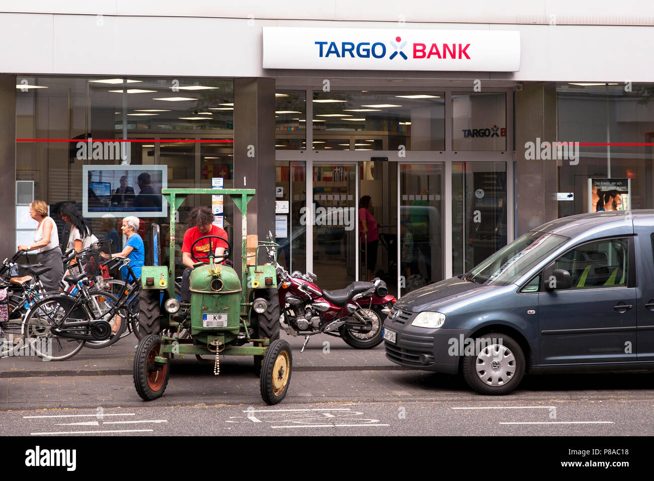 L'uomo con il trattore di fronte alla Banca Targo sulla Neusser Street nel quartiere Nippes a Colonia, Germania. Mann auf Traktor vor der Targo Bank auf der N Foto Stock