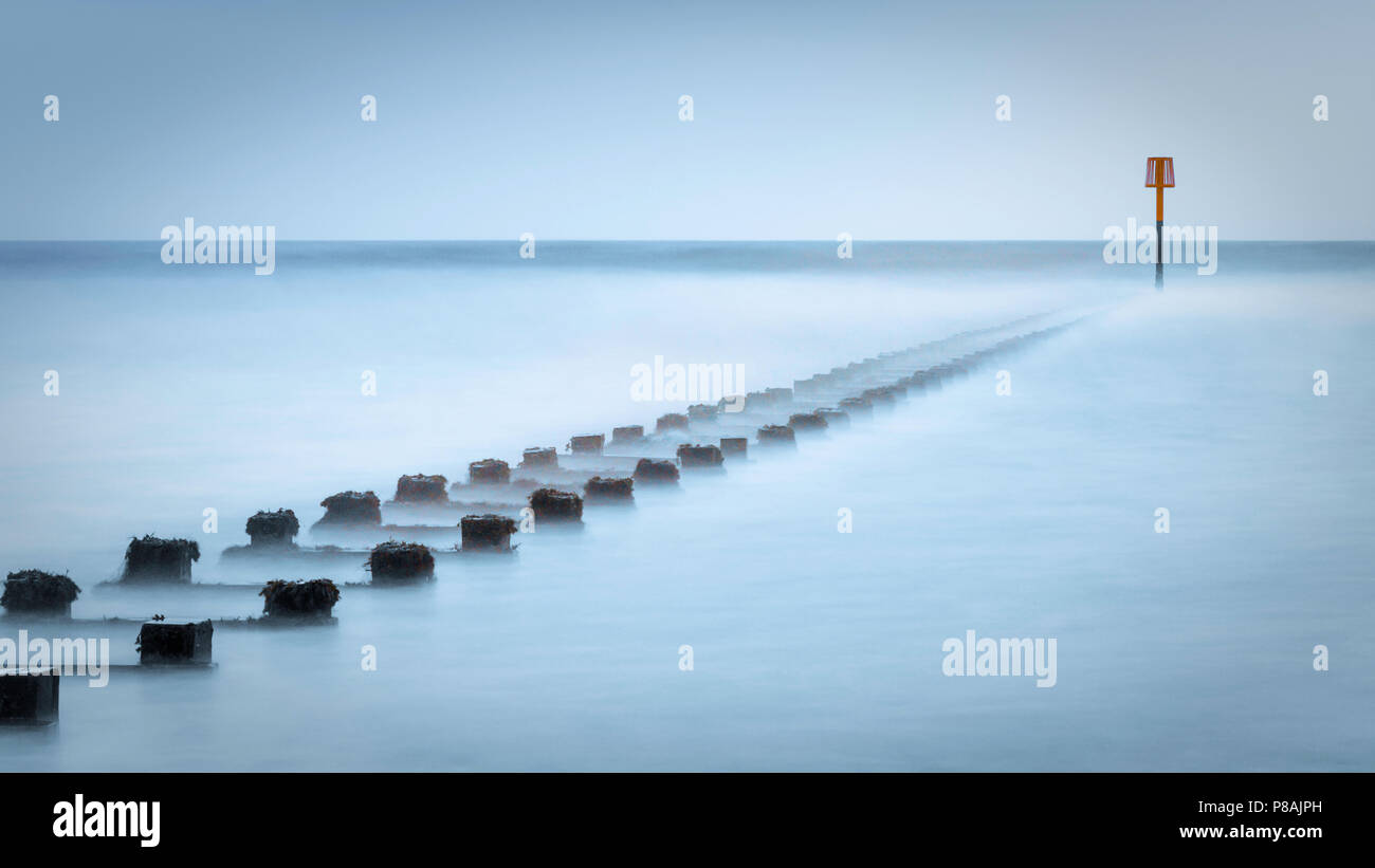 Una lunga esposizione di un frangiflutti coperti dalle onde dare un mistico sentimento di disagio. Foto Stock