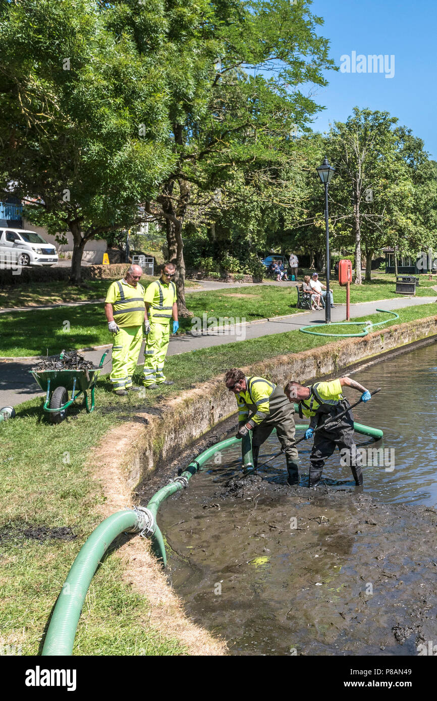 Lavoratori che utilizzano una pompa di aspirazione per rimuovere il fango e limo in un lago. Foto Stock