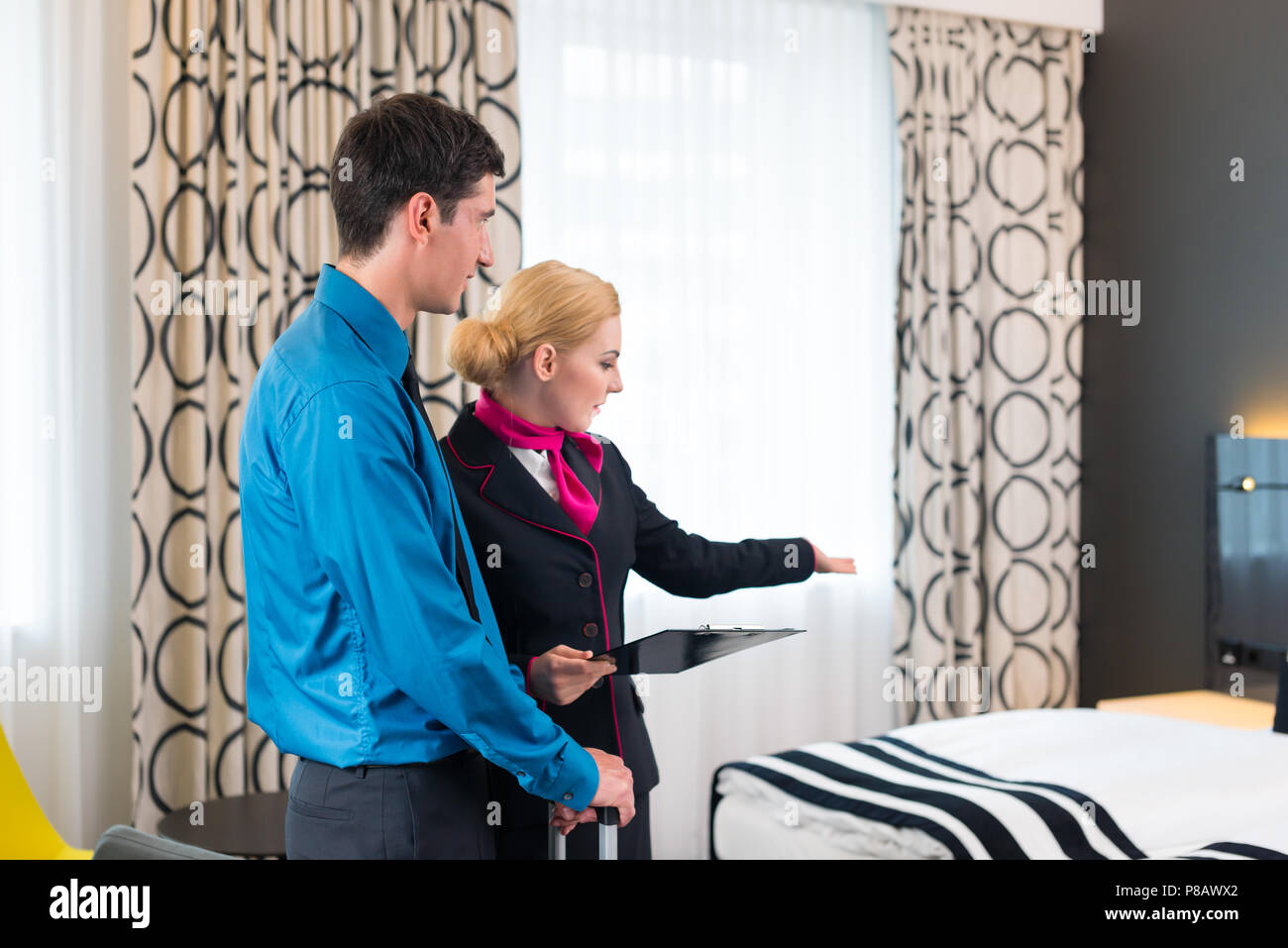 Il responsabile dell'albergo accogliente che mostra guest room Foto Stock