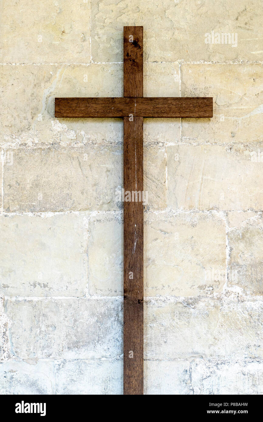 Vecchia croce di legno sul muro di pietra Foto Stock