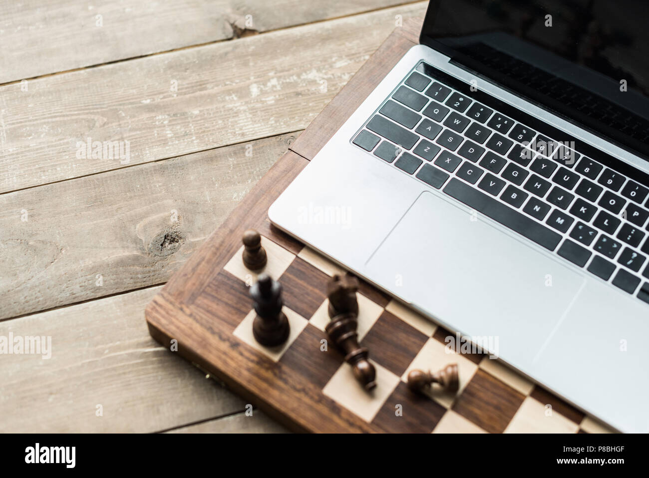 Scacchiera con pezzi di scacchi e portatile su rustico superficie in legno  Foto stock - Alamy