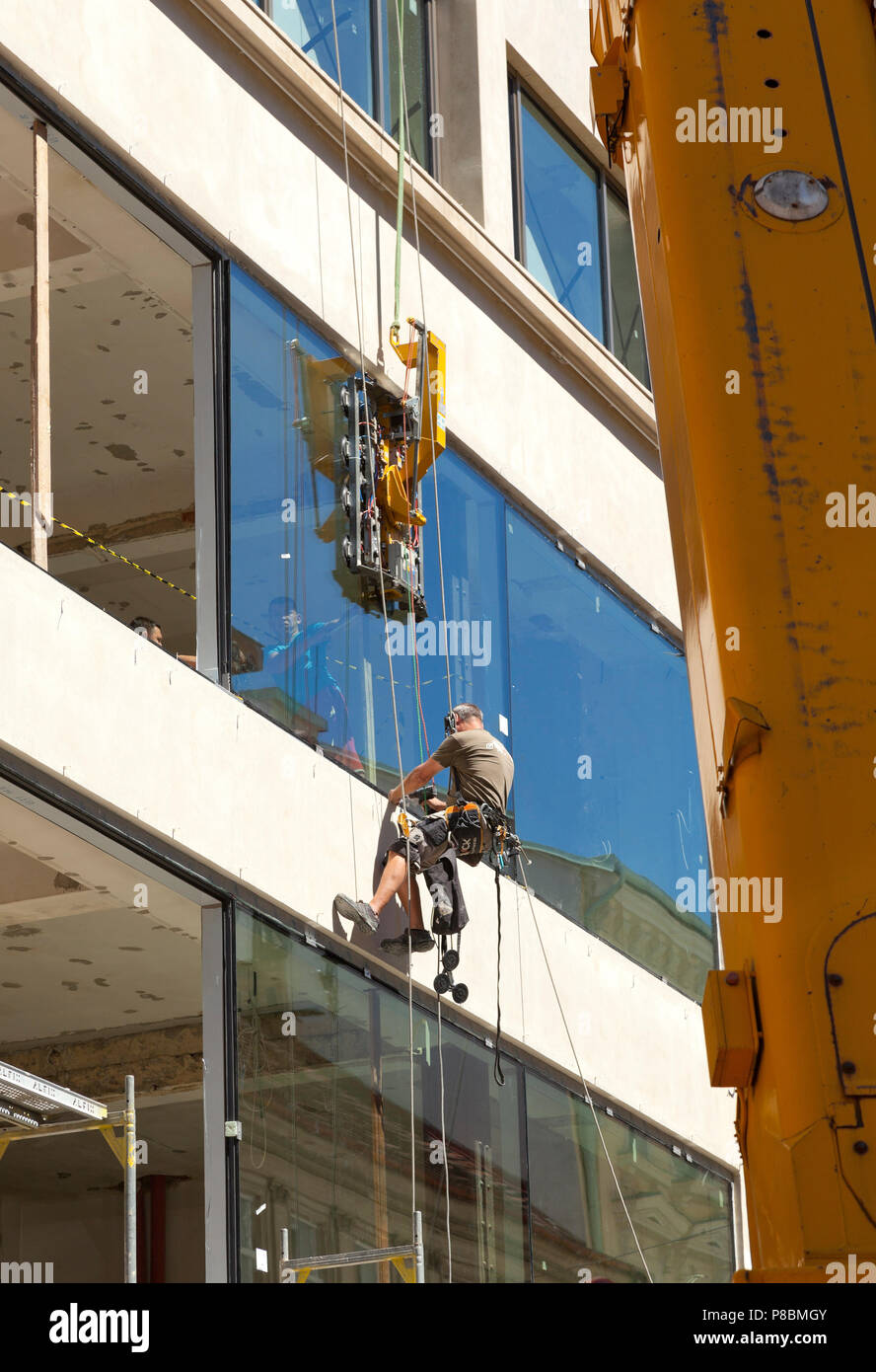 Costruzione di contattori installazione di grandi pannelli di vetro in un edificio di apertura Foto Stock