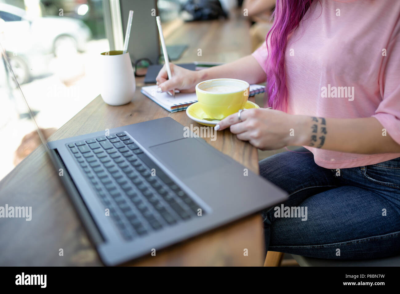 Donna digitando su notebook con schermo vuoto, seduti a un tavolo di legno Foto Stock