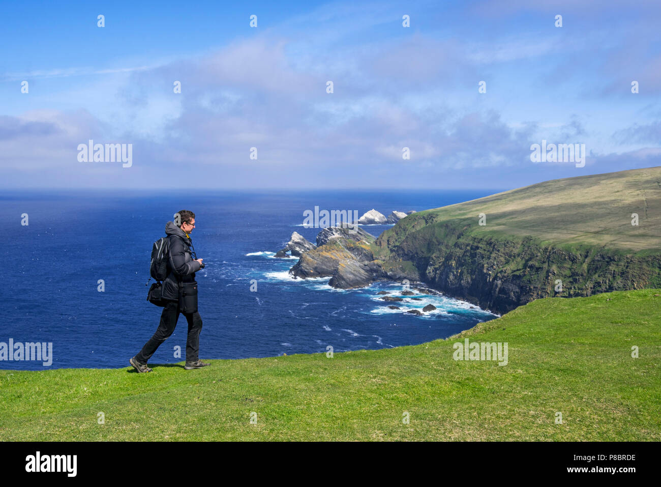 Fotografo di natura guarda la linea costiera con scogliere sul mare e pile, home all allevamento di uccelli di mare a Hermaness, Unst, isole Shetland, Scotland, Regno Unito Foto Stock