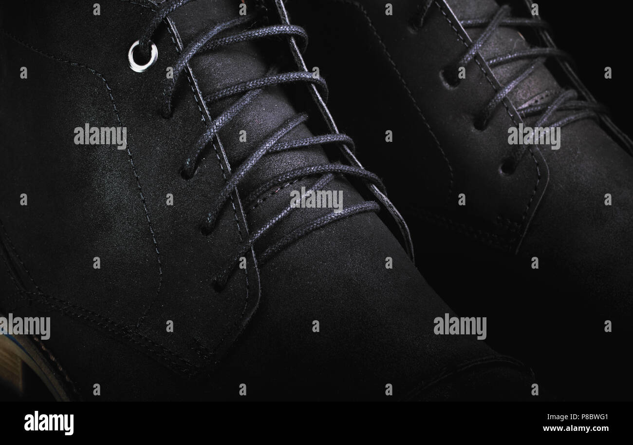 Uomo in pelle nera stivali scarpe con lacci macro closeup, sfondo nero in chiave di basso Foto Stock