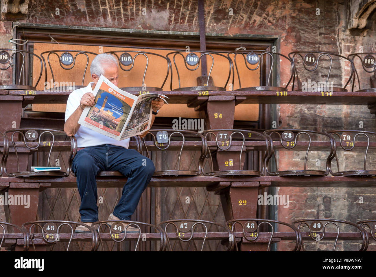 Un uomo che legge il giornale mentre in attesa per il Palio di Siena, Ilatly Foto Stock