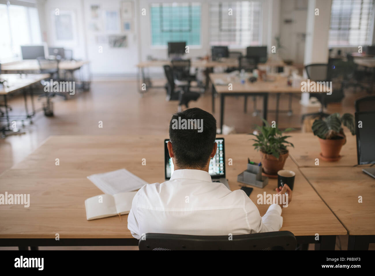 Imprenditore lavora da solo alla sua scrivania in un ufficio Foto Stock