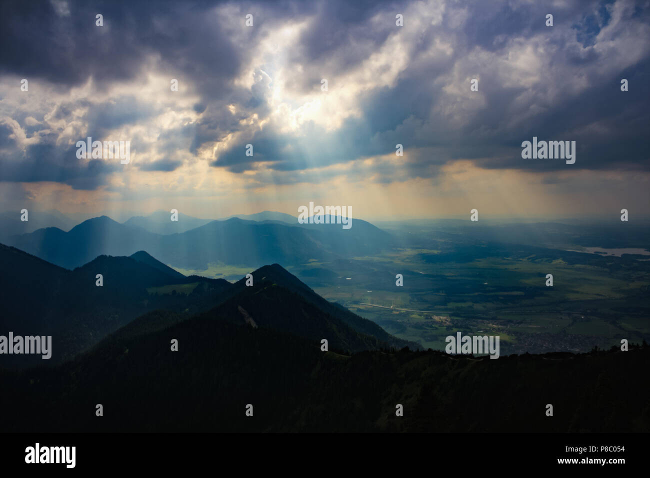 Raggi di sole brilla luminosa attraverso il buio e nuvole pesanti sulle montagne e il paesaggio di un temporale atmosfera picco di montagna sulle alpi bavaresi vicino a Monaco di Baviera Foto Stock