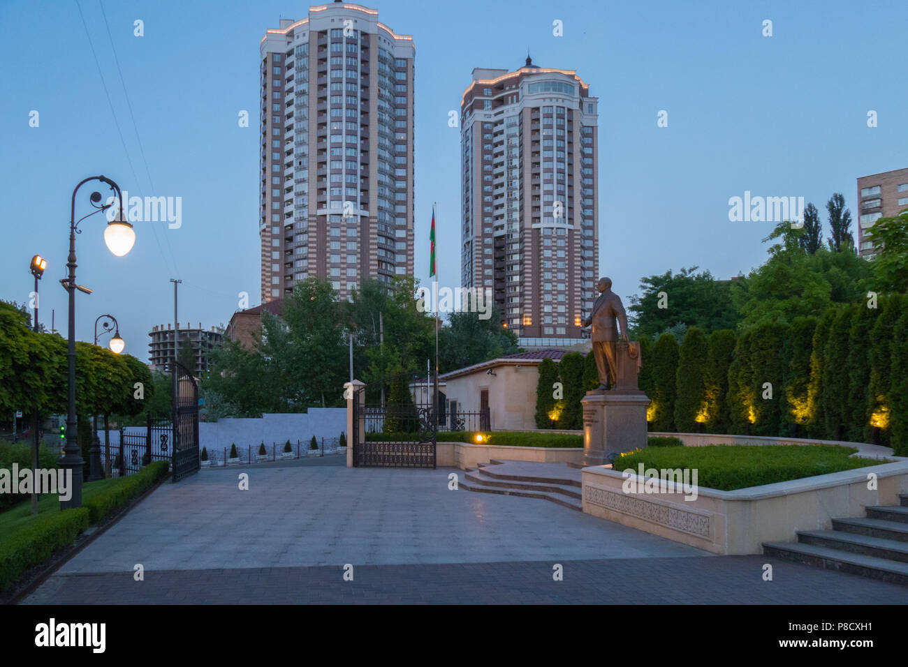 Paesaggio serale di edifici ad alta puntella il firmamento e un monumento nel verde degli alberi contro il loro background . Per il vostro design Foto Stock