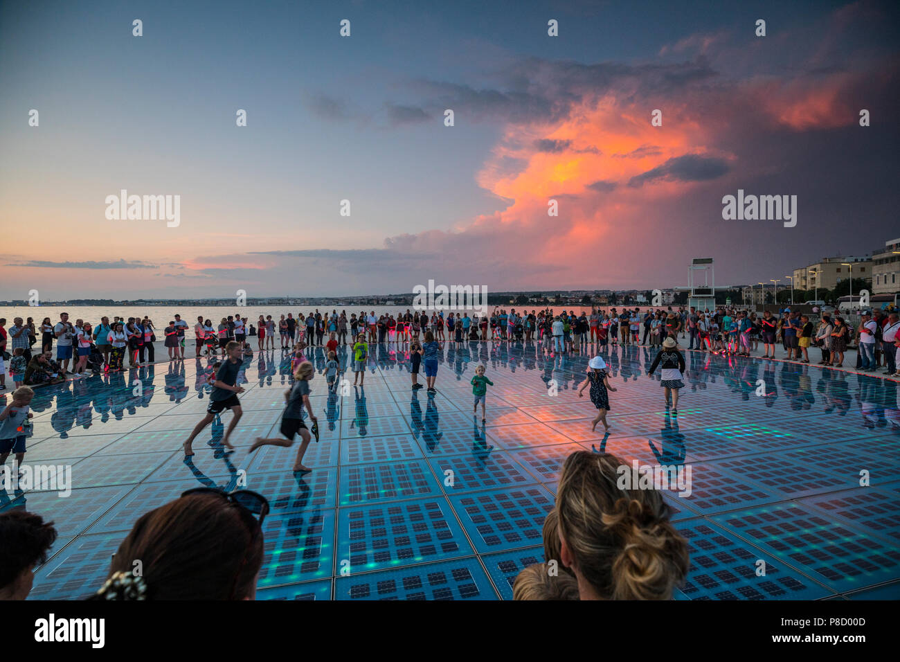 Bambini che giocano sul monumento saluti al sole in Zadar al tramonto Foto Stock