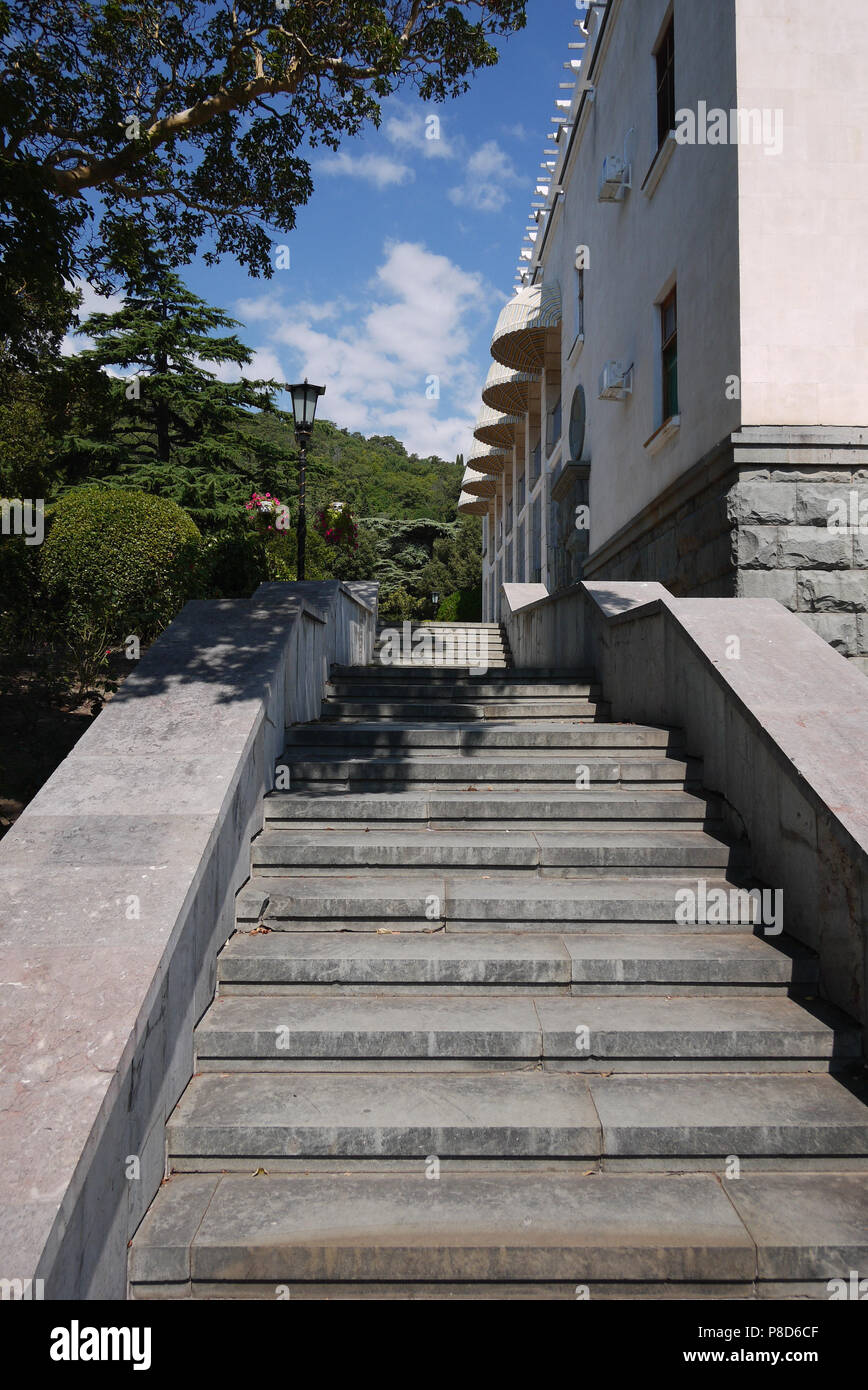 Una scaletta con gradini di granito salendo lungo la costruzione e pendii delle montagne in lontananza . Per il vostro design Foto Stock