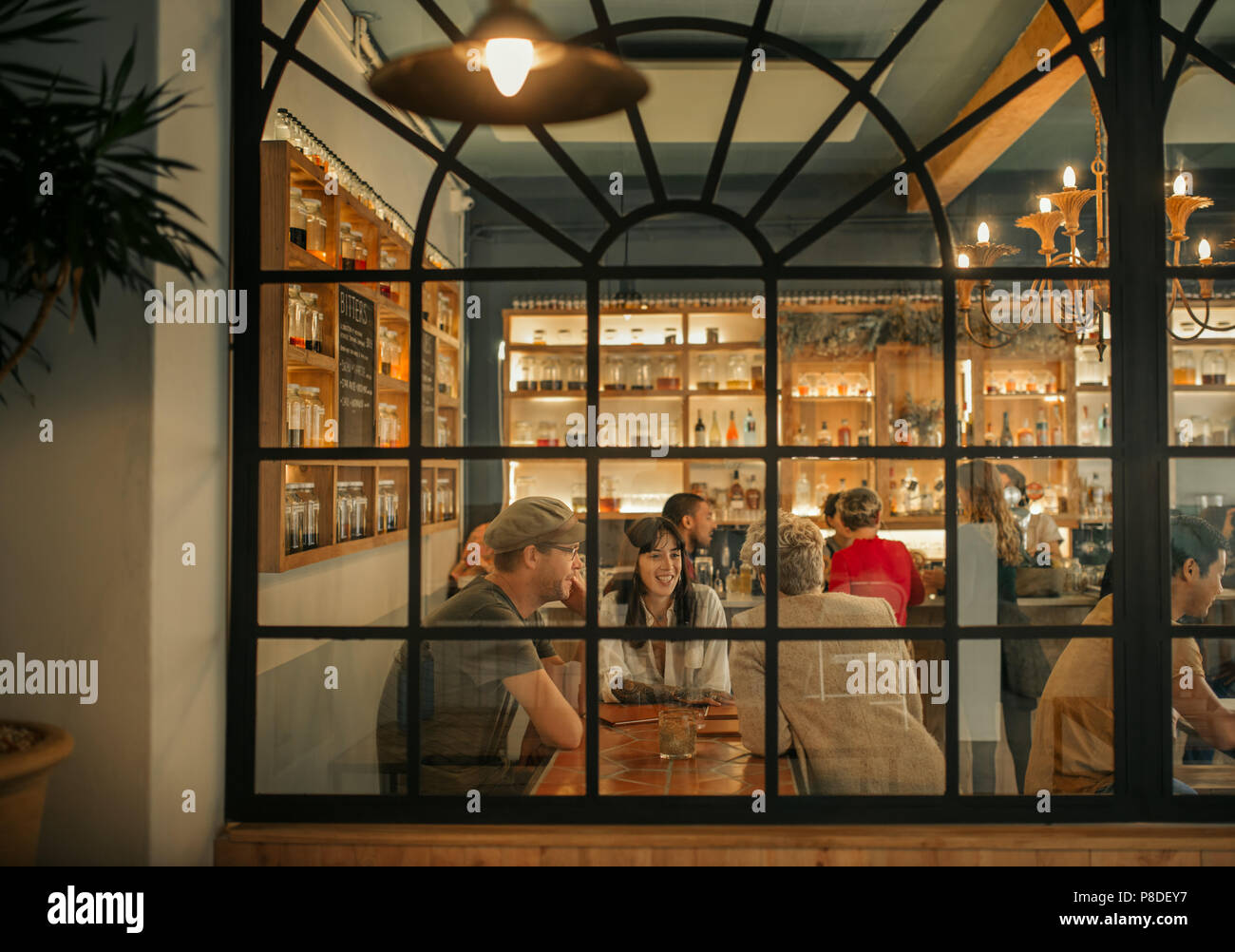 Sorridente giovani amici seduti insieme all'interno di un bar alla moda Foto Stock