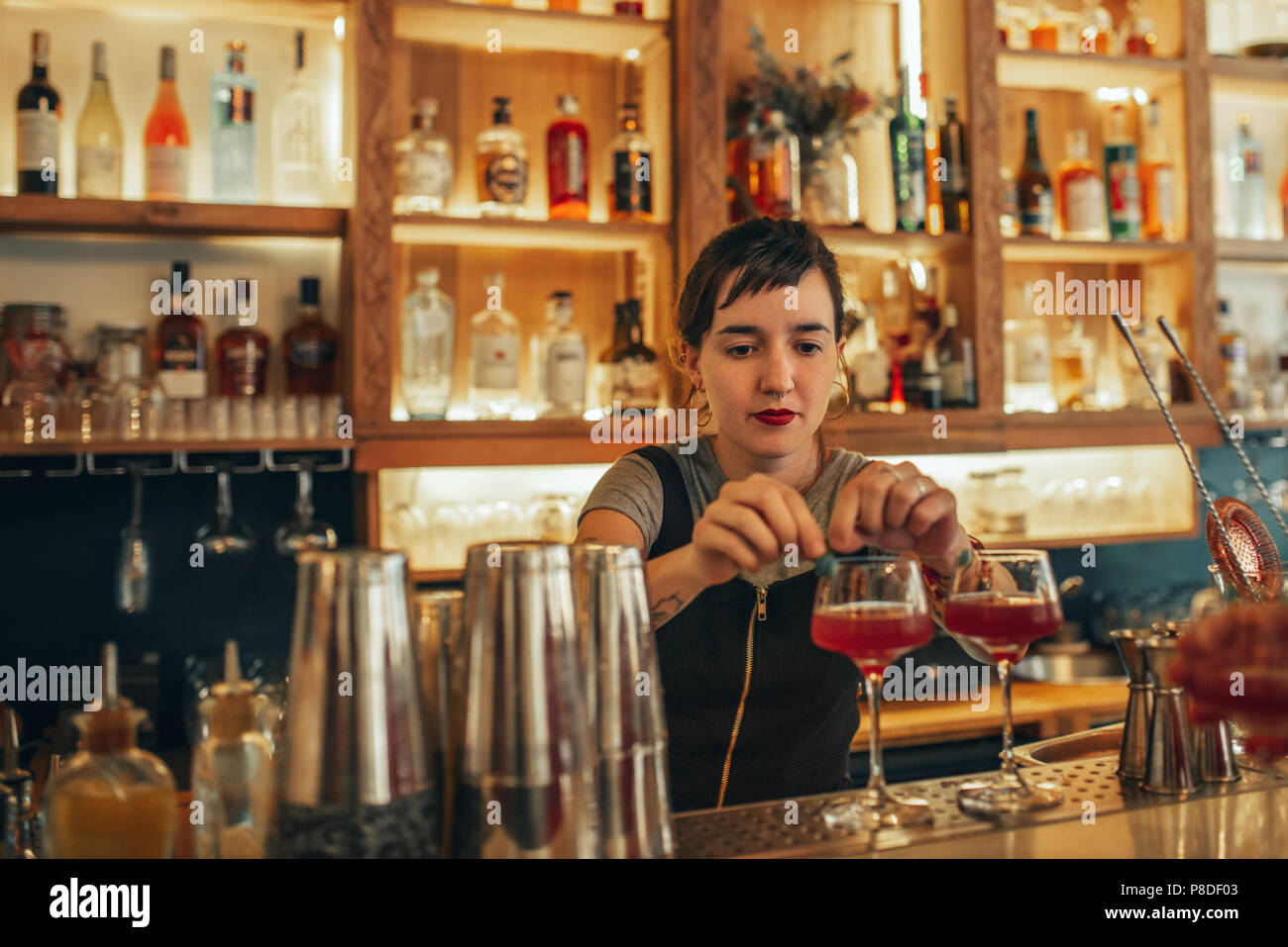 Giovane barista in piedi dietro un banco bar cocktail rendendo Foto Stock
