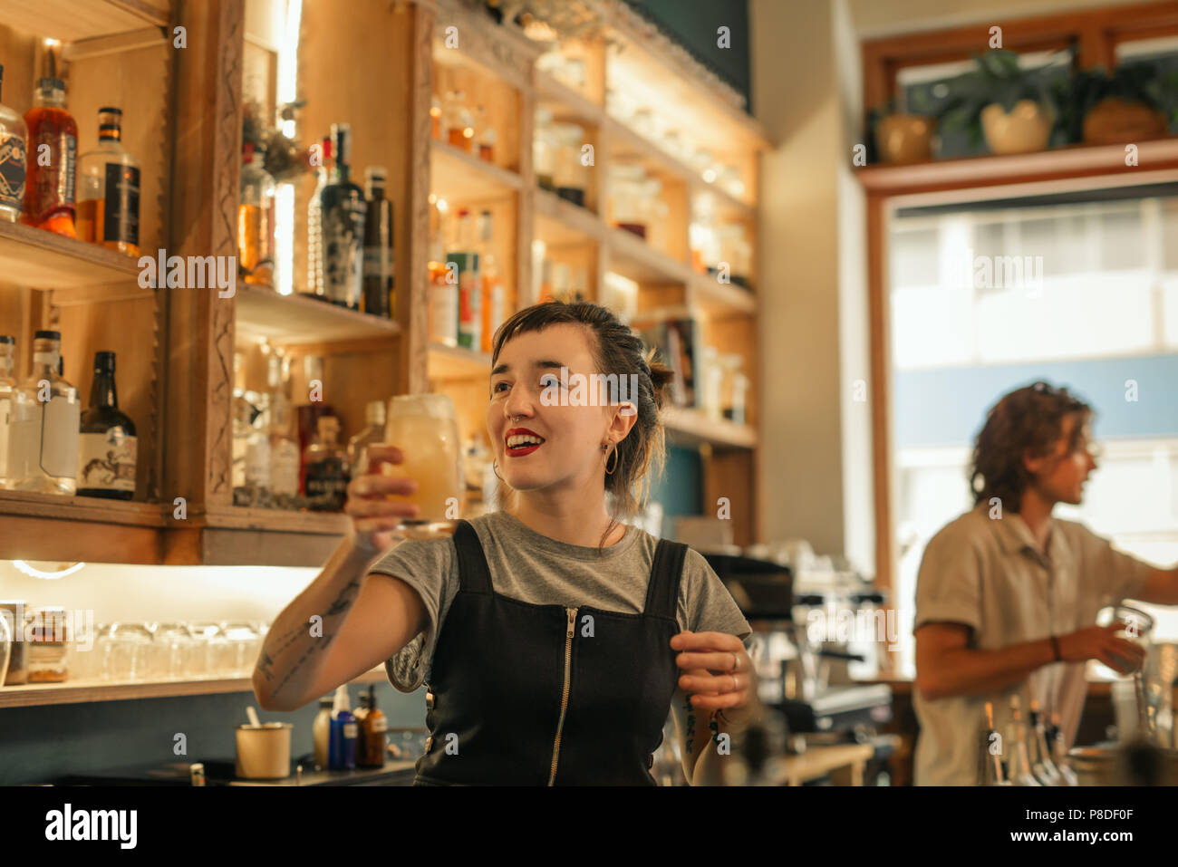 Sorridente giovane barista rendendo cocktail in un bar Foto Stock