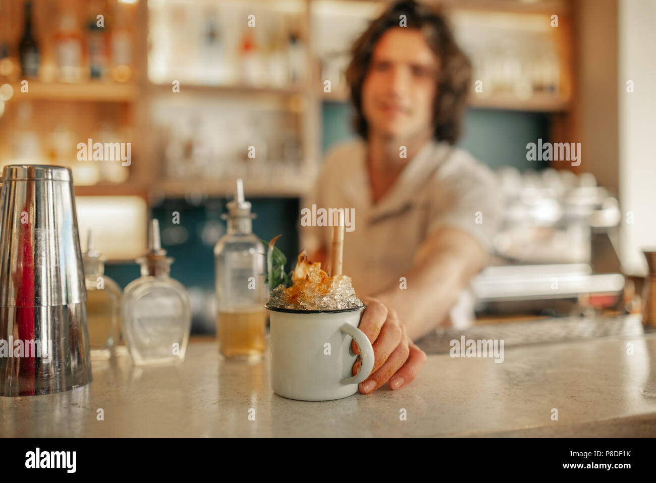Il Barista serve bevande dietro il bancone di un bar alla moda Foto Stock