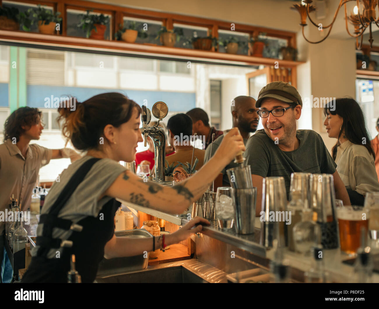 Sorridente patrono ordinare un drink in un bar alla moda Foto Stock